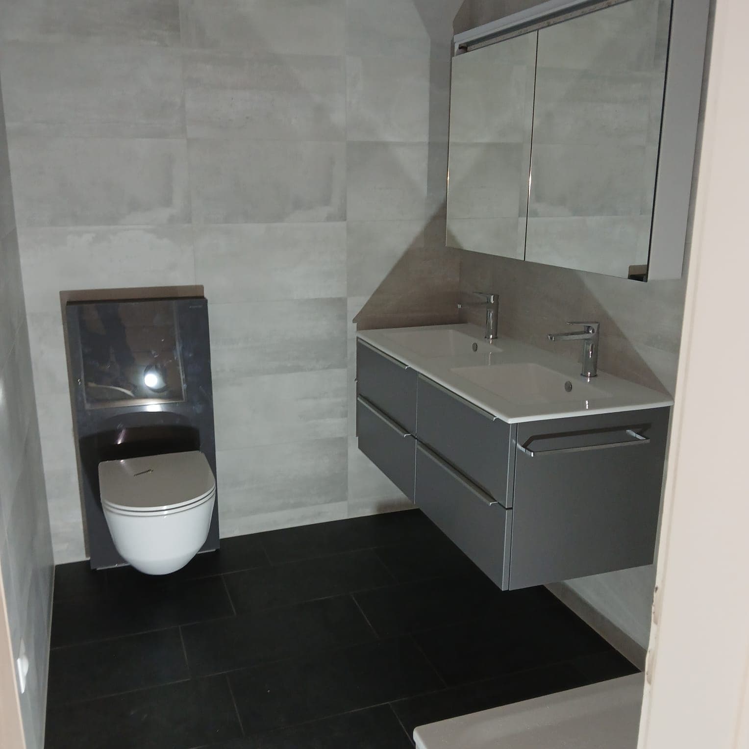 Salle de bains rénovée par VCS Maintenance : WC suspendu, double vasque et meuble gris